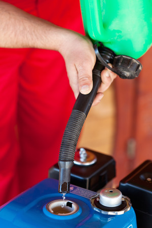 Man hands pouring gasolene into a small motorfrom a canister - closeupの写真素材