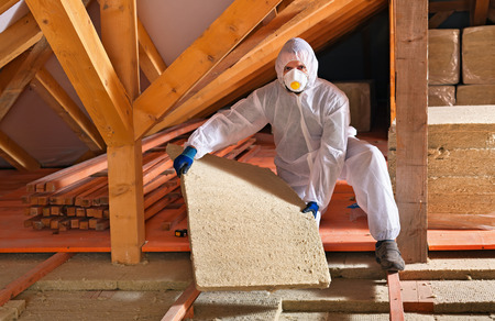 Man laying thermal insulation layer under the roof - using mineral wool panelsの写真素材