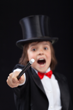 Young wizard or magician conjuring with magic wand on black background - focus on tip of wandの写真素材