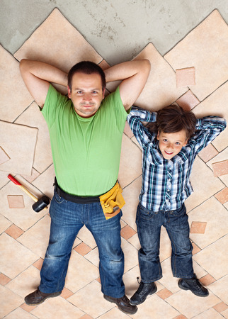 Father and son resting on unfinished floor tiles surface - resting after workの写真素材