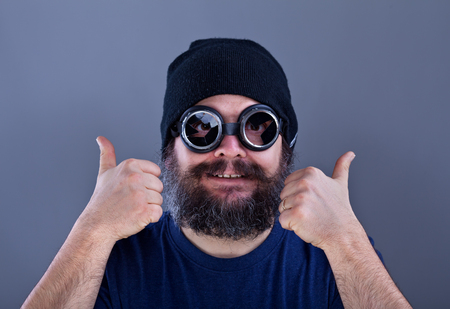 Weird man with large beard likes explosive offer - thumbs up with broken welding gogglesの写真素材