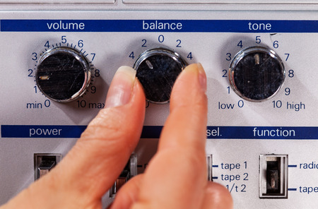Woman hand adjusting controls of an old retro music player - closeup on fingers and buttonsの写真素材