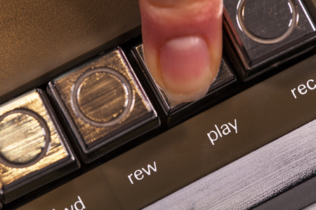 Finger pressing retro play button on vintage music player - macro closeup