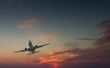 Commercial airliner taking off or landing against dramatic red blue sky - with landing gear halfway outの写真素材