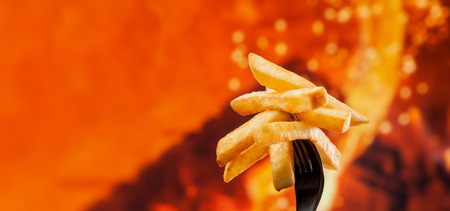 Delicious french fries on a fork - fire background with copy space, close up