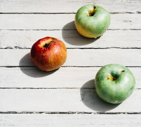 One red Apple and two green apples lie on a white wooden background. Fresh apples in the kitchen on the table, three apples.の写真素材