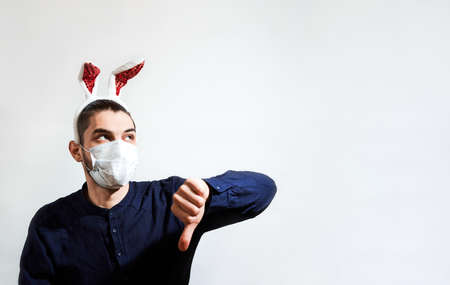 Caucasian man with red hare ears wears medical protective mask and puts on dislike with one hand....