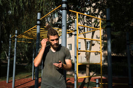 Active lifestyle concept. Young Caucasian man with a beard and dreadlocks puts on wireless...
