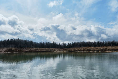 Beautiful view of sand dunes and quarries with water in cloudy sunny weather in spring. Landscapes of Russia Moscow region. Artificially dug pits and ponds or lakes.の写真素材