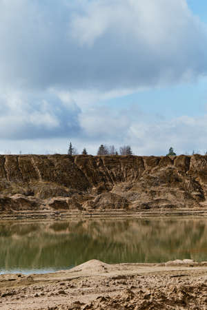 Beautiful view of sand dunes and quarries with water in cloudy sunny weather in spring. Landscapes of Russia Moscow region. Artificially dug pits and ponds or lakes.の写真素材