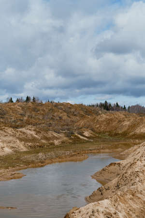 Beautiful view of sand dunes and quarries with water in cloudy sunny weather in spring. Landscapes of Russia Moscow region. Artificially dug pits and ponds or lakes.の写真素材