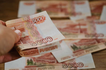 Human holds paper banknote of five thousand rubles with hand. Economics and finance of Russian...