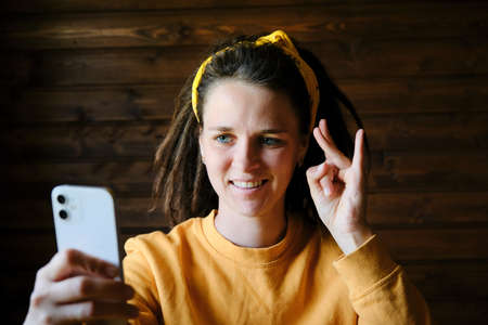 body language concept. hard hearing people. Young European woman with dreadlocks talks over video link using sign language and smiles. Person with disabilities lives normal life.の写真素材