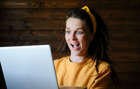 The concept of winning lottery. Young Caucasian woman with blue eyes and dreadlocks in yellow hoodie...