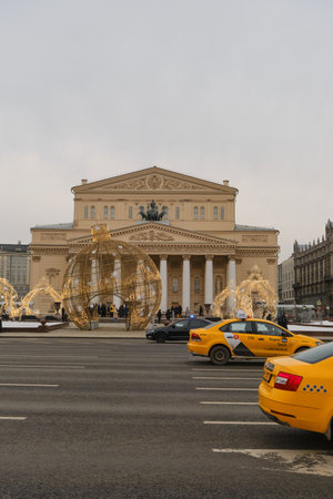 Russia Moscow - February 2023. Facade of the historical building of architecture Bolshoi Theater in city center. Christmas garlands and decorations on the street. Cars and yellow taxis stuck in traffic.のeditorial素材