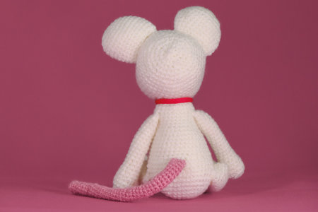 Amigurumi one white mouse with big ears and long nose on a pink background. rear view. A soft DIY toy made of natural cotton and wool. Cute little rat crocheted, handmade art.の写真素材