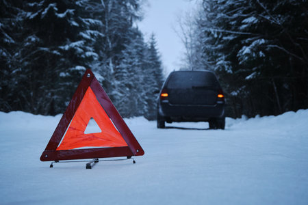 The sign is a red triangle on a rural snowy winter forest road. A broken-down car after the incident. rear viewの写真素材