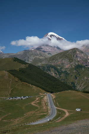 Nature of the Northern Caucasus. The snowy peak of Mount Kazbek. View from the peak in the village of Stepantsminda, Kazbegi. Blue cloudy sky. Trip to Georgia. A popular point of view for touristsの写真素材