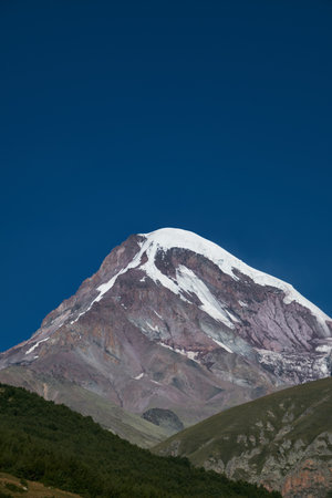 Nature of the Northern Caucasus. The snowy peak of Mount Kazbek. View from the peak in the village of Stepantsminda, Kazbegi. Blue cloudless sky. Trip to Georgiaの写真素材
