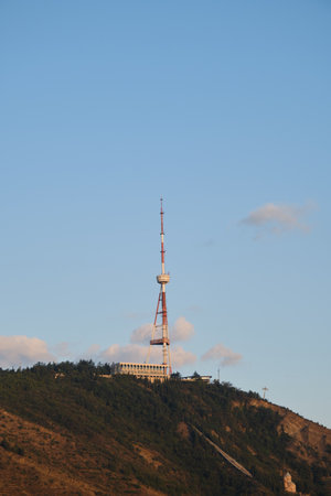 A tall TV tower in the center of Tbilisi on a mountain on the territory of the Mtatsminda amusement park. The capital of Georgia in the morning at dawn, Television and radio signalの写真素材