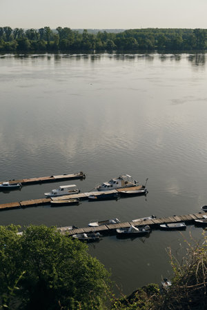 Small fishing rowboats and motorboats stand on the wooden dock of the Danube River in Zemun on a sunny, calm morning. View from above.の写真素材