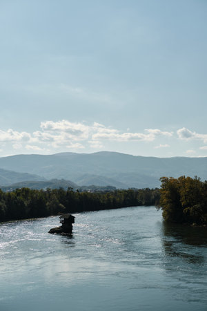 On a small rocky ledge in the middle of the winding Drina River with clear turquoise water, on the...