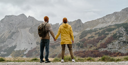 Breathtaking mountain landscape with happy young couple holding their hands. Rear view. Travel around the world concept. Montenegro country, Durmitor National Park. Saddle Pass in autumn seasonの写真素材