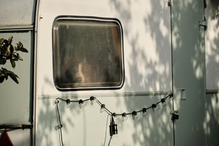An Australian Shepherd sits in a mobile home trailer parked at a campsite on a sunny day. Travel with pets concept. Camping in nature. The dog is looking out the windowの写真素材