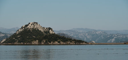 A stunning view of the lush mountains and reed-covered banks under a clear blue sky, reflecting...
