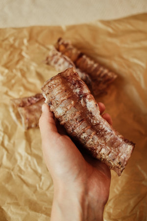 A hand holding a natural dried beef trachea - a healthy chew treat for dogs. Close-up shot...