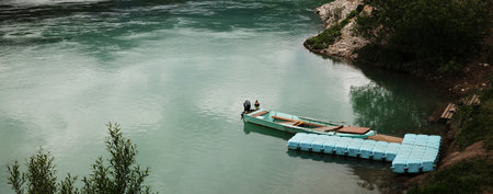 A small wooden boat anchored at a floating dock on the calm waters of the Drina River in Serbia country in spring season. Web bannerの写真素材