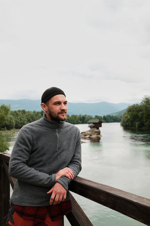Smiling man in casual clothes enjoying the view of the Drina River and the iconic house on the rock. A popular tourist destination. Serbia country in spring seasonの写真素材