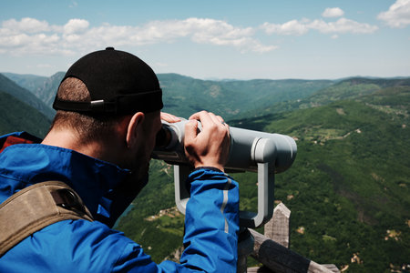 Close-up of man observing the mountain landscape through a telescope on a scenic lookout in Tara...