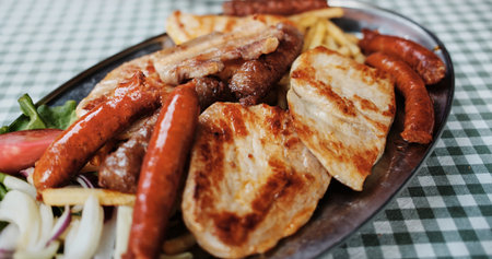 Close-up of a traditional Serbian grilled meat platter with sausages, pork and French fries served...