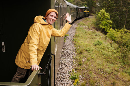 A young woman waves from a vintage train as it curves through a mountain forest on the Shargan Eight...