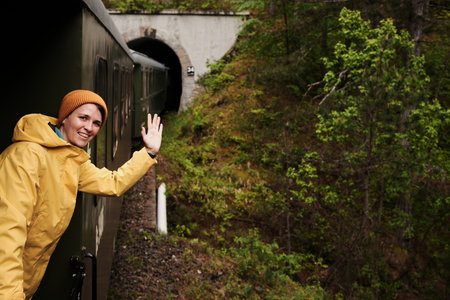 A young woman waves from a vintage train as it curves through a mountain forest on the Shargan Eight...