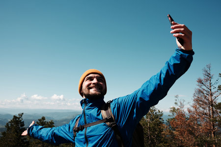 Happy tourist stretching arms wide for a selfie, enjoying the scenic view from Tornik peak. Serbia country during spring. Travel blogger making video outdoorの写真素材