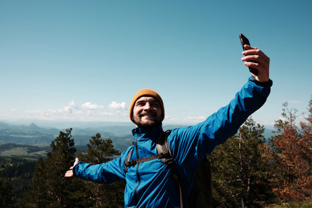 Happy tourist stretching arms wide for a selfie, enjoying the scenic view from Tornik peak. Serbia country during spring. Travel blogger making video outdoorの写真素材