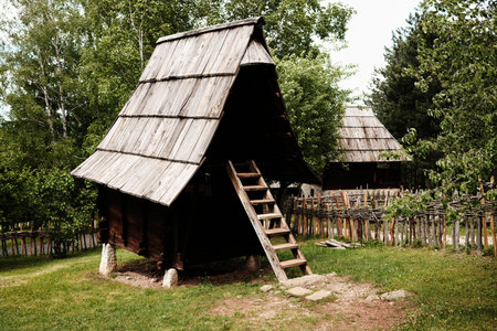 A small wooden hut on stilts with a steep roof in a traditional Serbian ethnovillage. Ethno village Staro Seloの写真素材