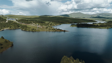 Aerial view of Ribnicko Lake in Zlatibor, Serbia, with rolling green hills and dramatic clouds in...