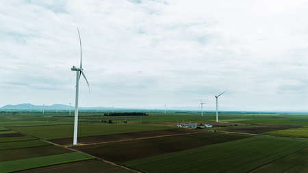 Aerial view of wind turbines on vast green fields in Vojvodina, Serbia, during springtime, with...