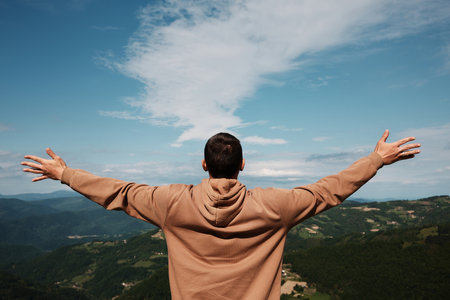 Man with outstretched arms embracing the mountain view in Serbia during a bright spring day. Rear...
