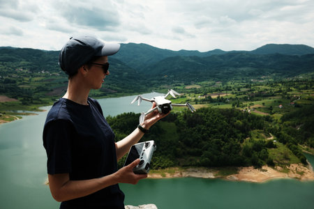 A woman holds a drone and controller above Lake Rovni in Serbia, enjoying the view from the cliff....