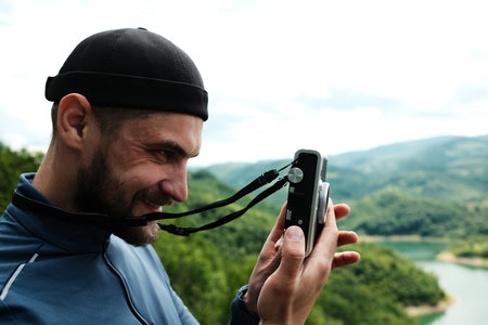 Side portrait of a man preparing to take a photo with an instant camera, enjoying the scenery at...
