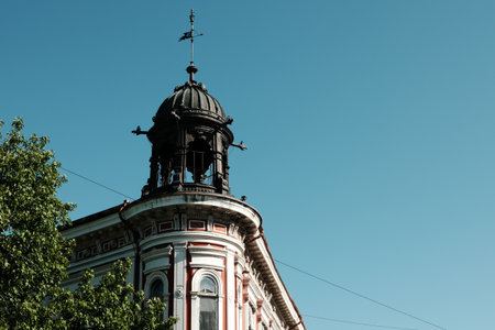 Historic red and white building with ornate tower and metal dome in Vrsac, Serbia, under clear blue...