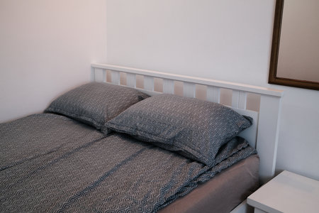 Neatly made bed with two patterned pillows and matching duvet cover in a minimalist bedroom setting....
