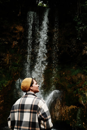 Young woman in plaid jacket enjoying view of Veliki Buk waterfall in Lisine reserve, Serbia country....
