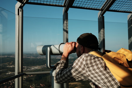 A young man using binoculars at the top of Avala Tower in Belgrade, Serbia, enjoying the panoramic...