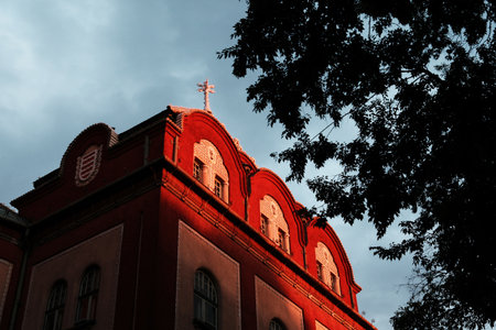 Decorative building facade in Subotica, Serbia, glowing in sunset light with a cloudy sky. Hungarian...