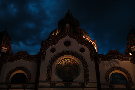 Subotica Synagogue illuminated at night with glowing windows and rich decorative details under a dark blue sky. Travel in Serbia country conceptの写真素材